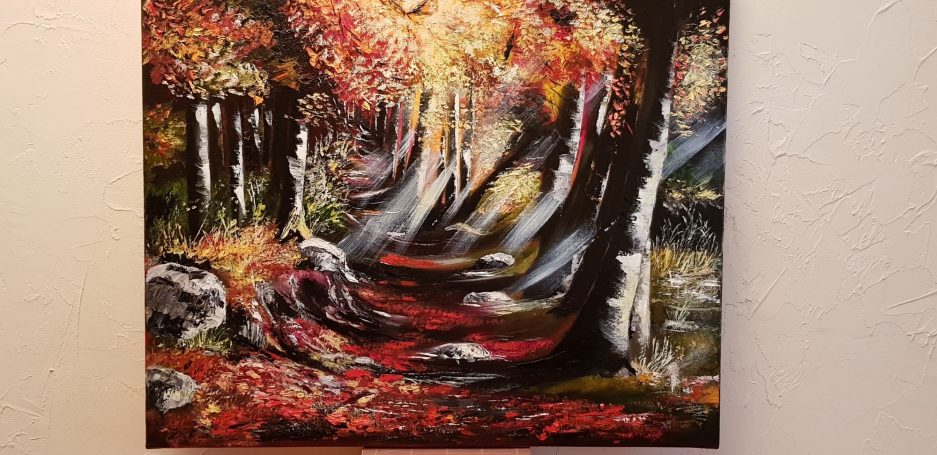 Forêt automnale avec des arbres colorés et un chemin bordé de feuilles.