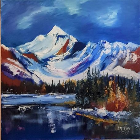Montagnes enneigées sous un ciel bleu avec un lac et des arbres colorés en automne.